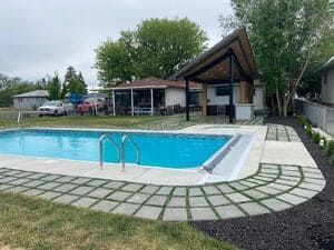There is a large swimming pool in the backyard of a house.