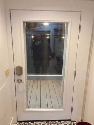 A white door with a glass window and a reflection of a person in it.