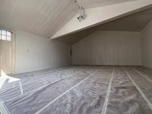 An empty room with a plastic sheet on the floor.