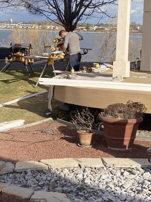 A man is working on a porch next to a body of water.