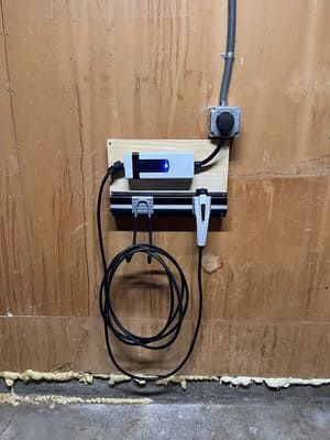 A car charger is hanging on a wooden wall.