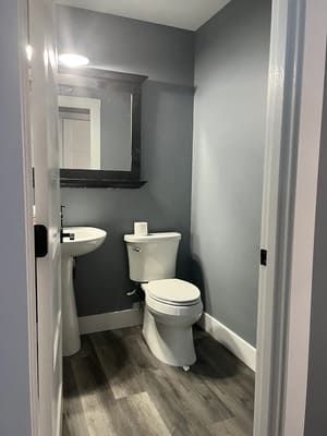 A bathroom with a toilet , sink and mirror.