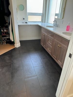 A bathroom with a sink , cabinets , and a window.