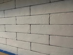 A close up of a white brick wall with blue tape on it.