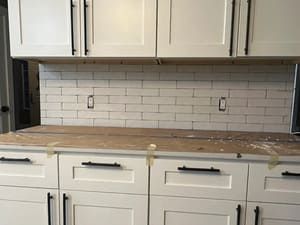 A kitchen with white cabinets and black handles is being remodeled.