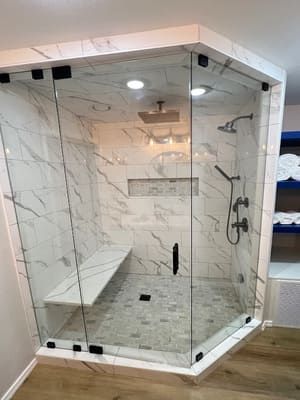 A shower with a bench in it and a glass door.
