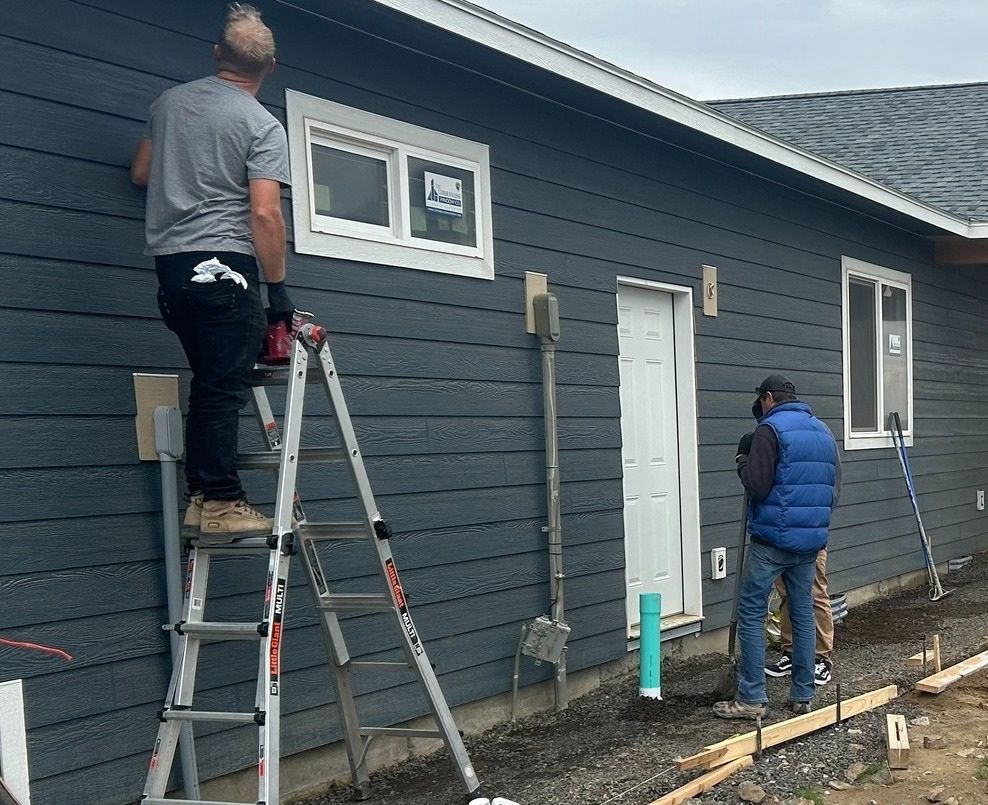 Two men are working on the side of a house.
