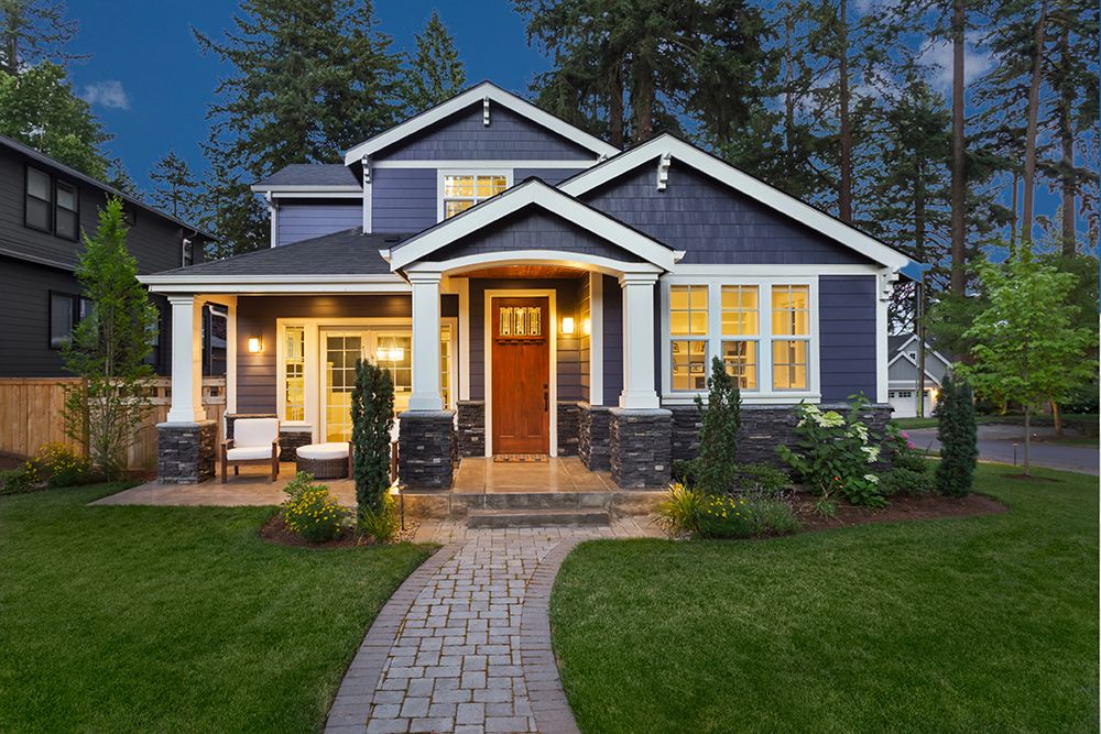 A blue and white house with a brick walkway leading to it.