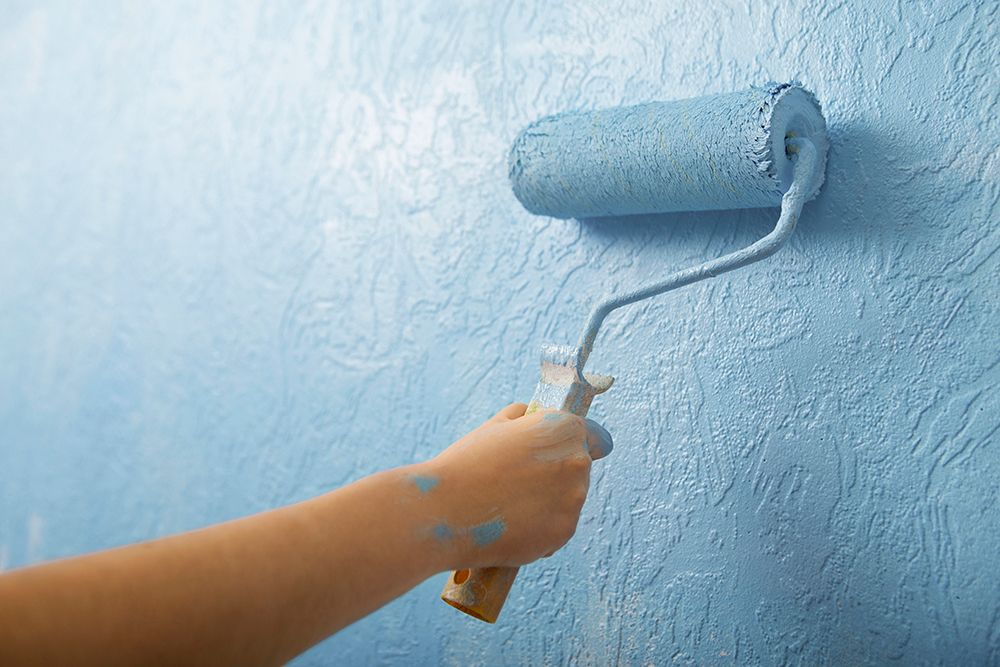 A person is painting a wall with a roller.