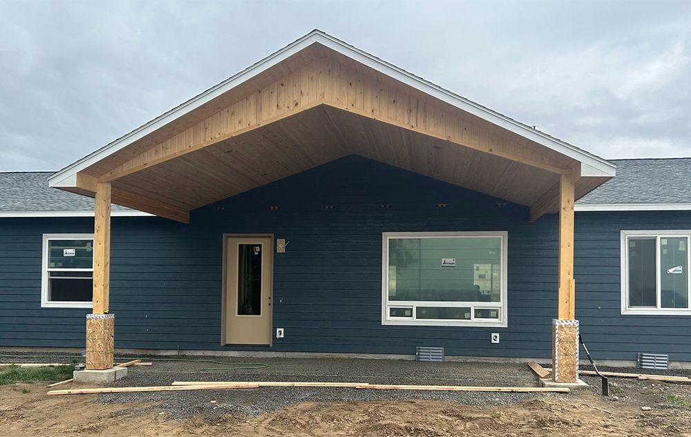 A blue house with a wooden porch and a wooden roof.