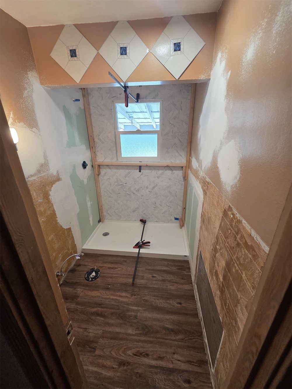 A bathroom is being remodeled with a shower and a window.