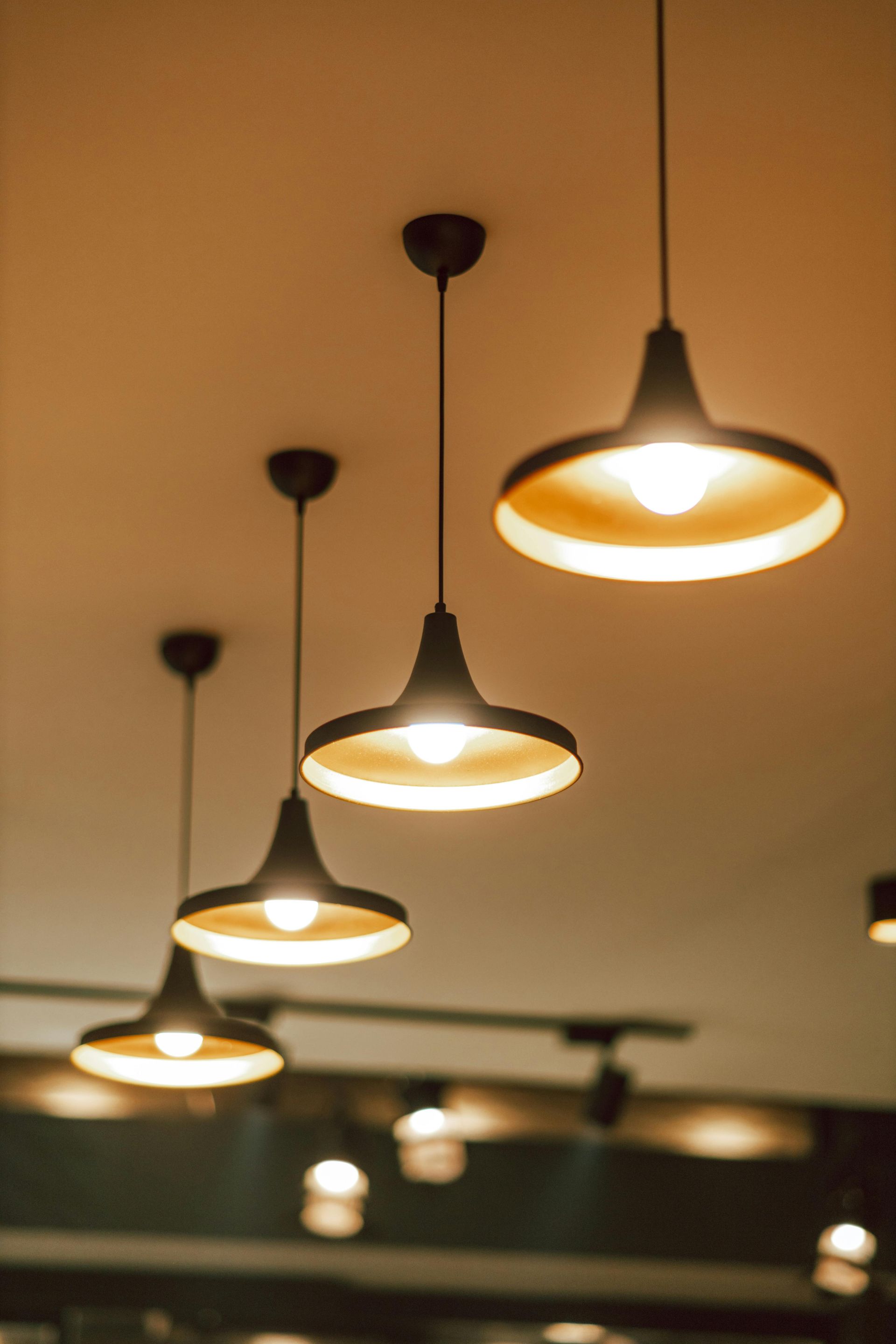 Three black pendant lights with glowing warm bulbs hanging from a ceiling indoors