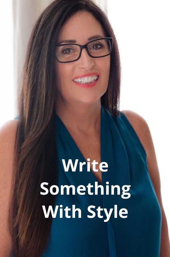 A woman wearing glasses and a blue shirt is smiling.