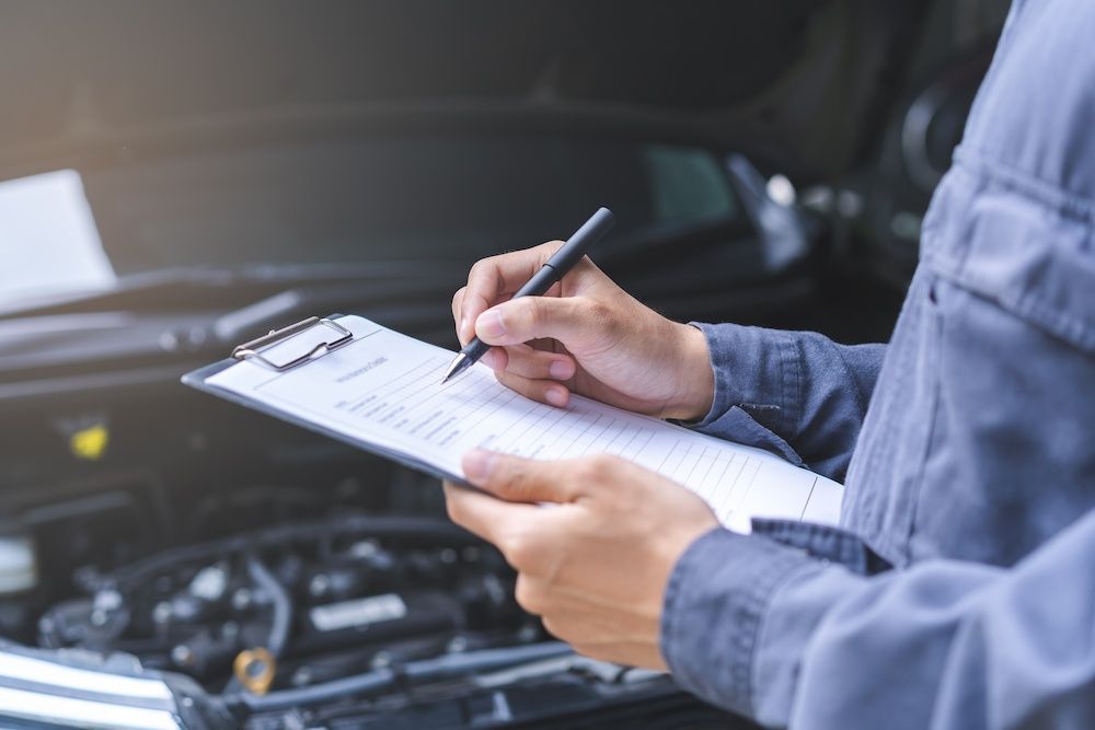 Person Holding a Clipboard and Pen While Inspecting a Car Engine — Precision Tuning in Cairns City, QLD