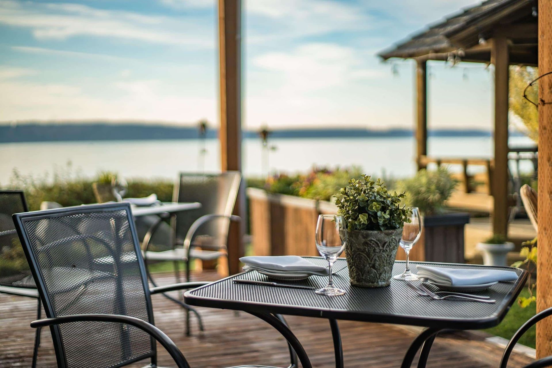 There is a long table and chairs under a pergola.