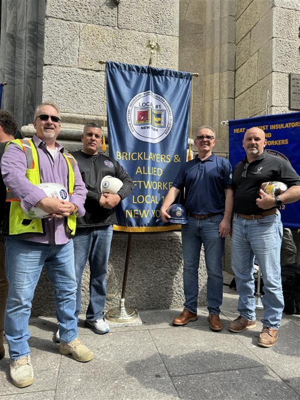 Four people holding stuffed penguins stand beside a blue Berkeley County banner outdoors.