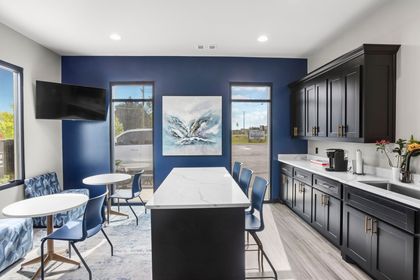 Modern kitchen with blue walls, black cabinets, white countertop, and a dining area.
