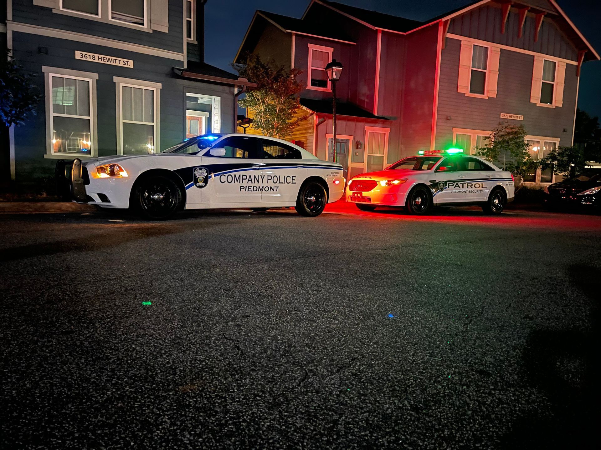 Police cars with flashing lights parked on a street in front of a house at night
