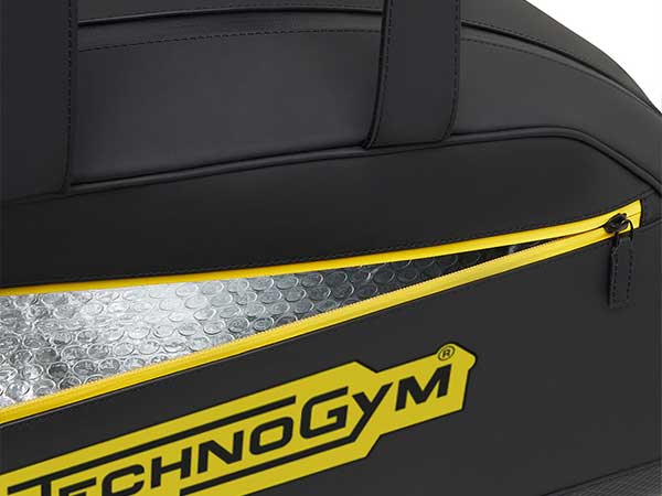 Close-up of a black gym bag with a yellow-zippered pocket showing an insulated, bubble-lined interior and Technogym logo.