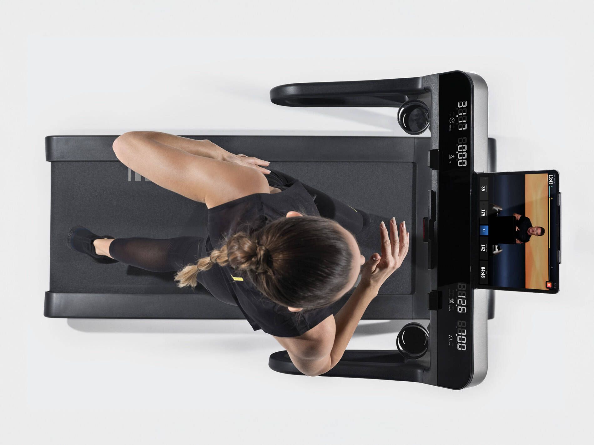 Top-down view of someone running on a treadmill with a digital screen displaying a workout class.