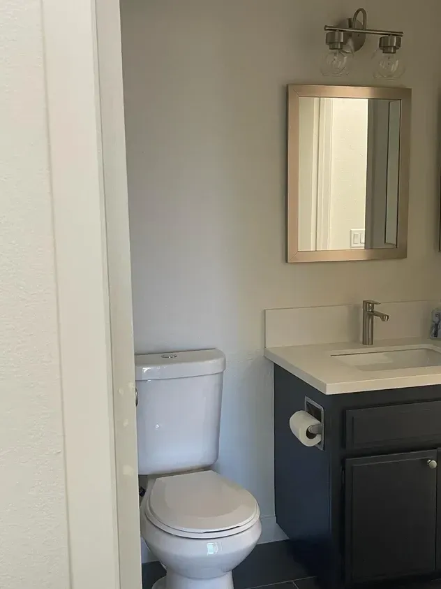 A bathroom with a toilet, sink and mirror.