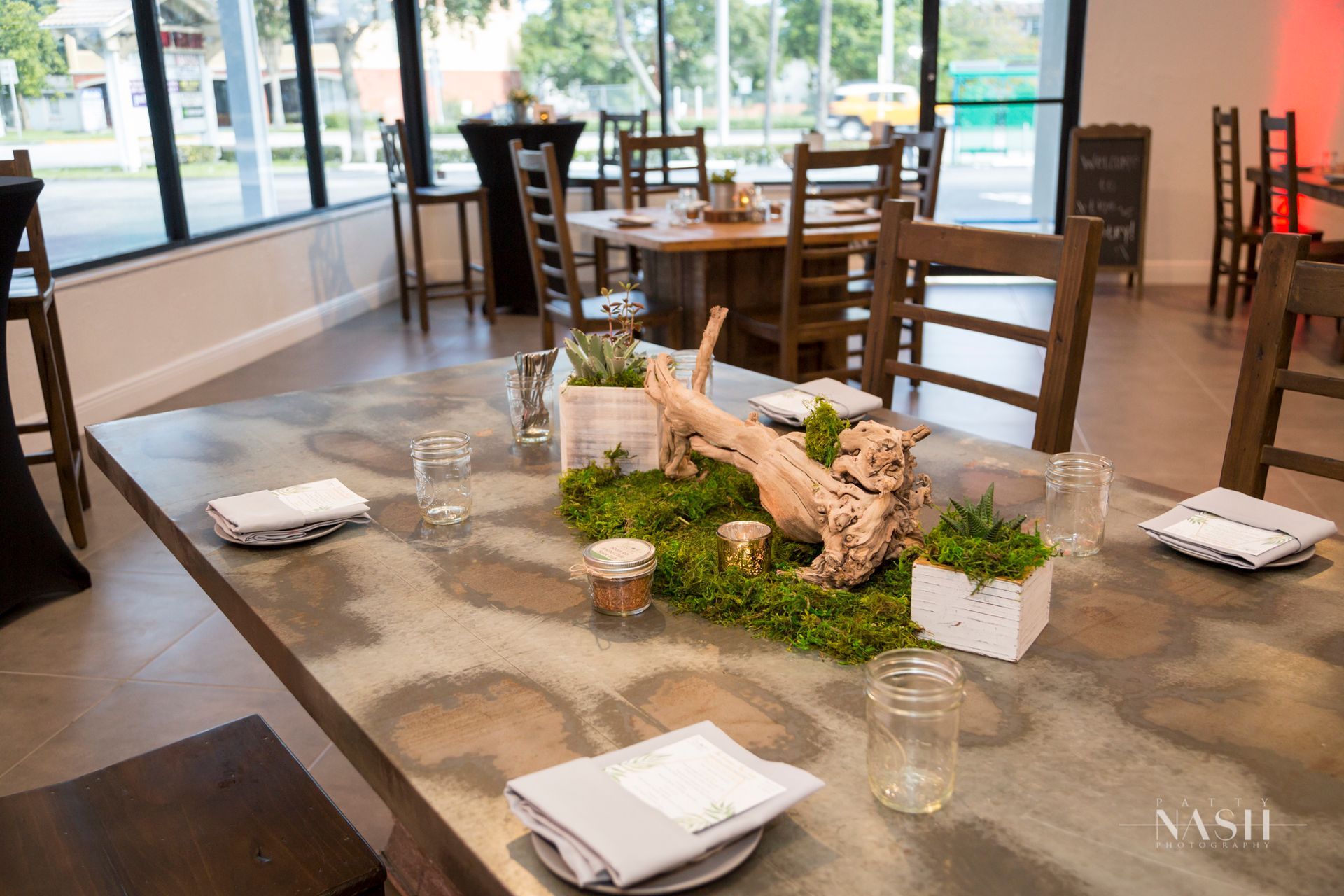 A table with plates , glasses , and a piece of driftwood on it in a restaurant.
