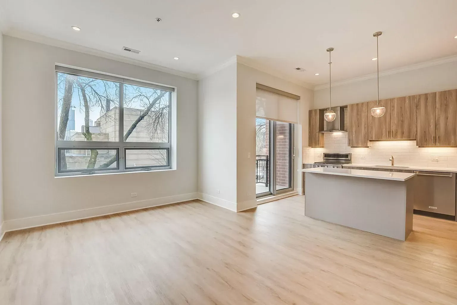an empty apartment with a kitchen and a large window .