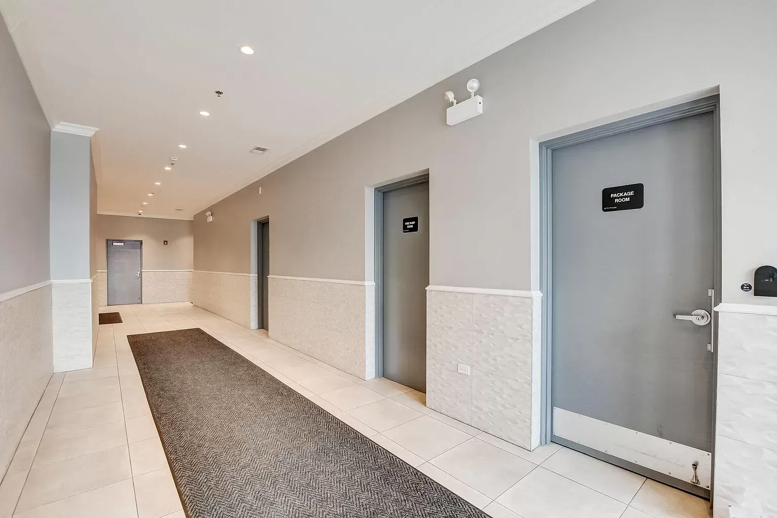 a long hallway with gray doors and a rug .