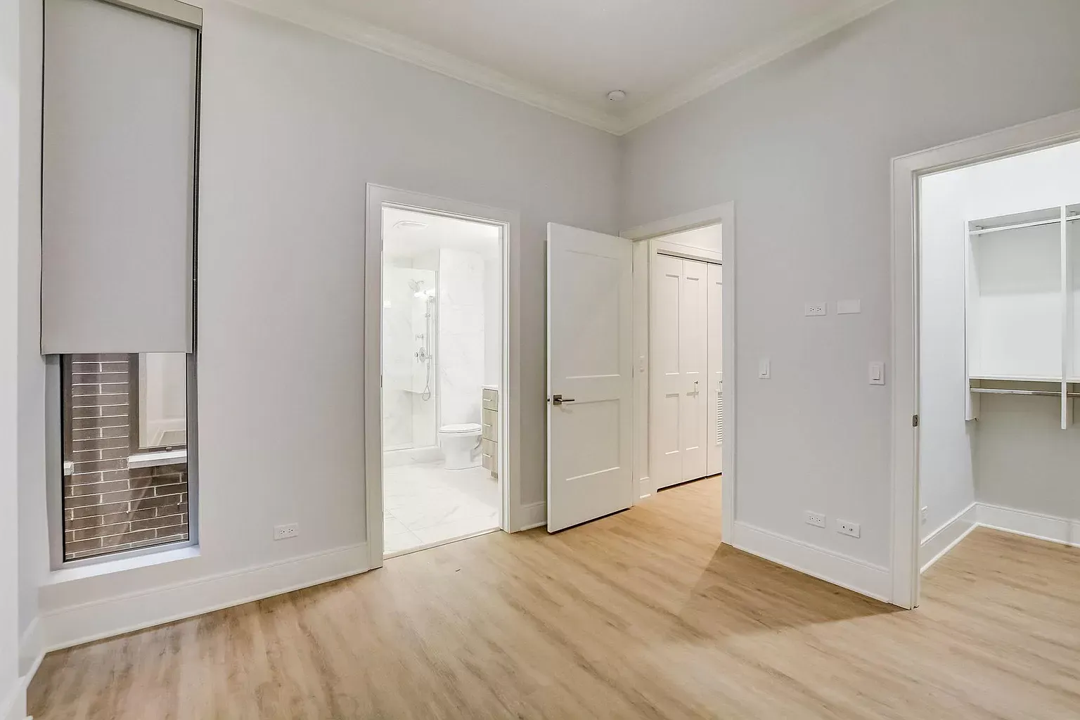 a bedroom with hardwood floors , white walls , and a walk in closet .