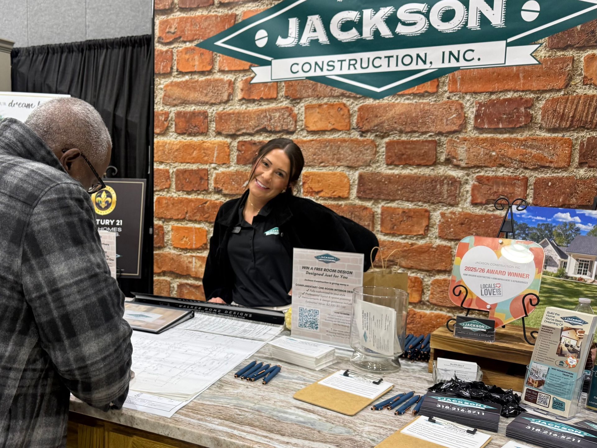Jackson Construction booth with a woman behind a table and a man speaking to her.