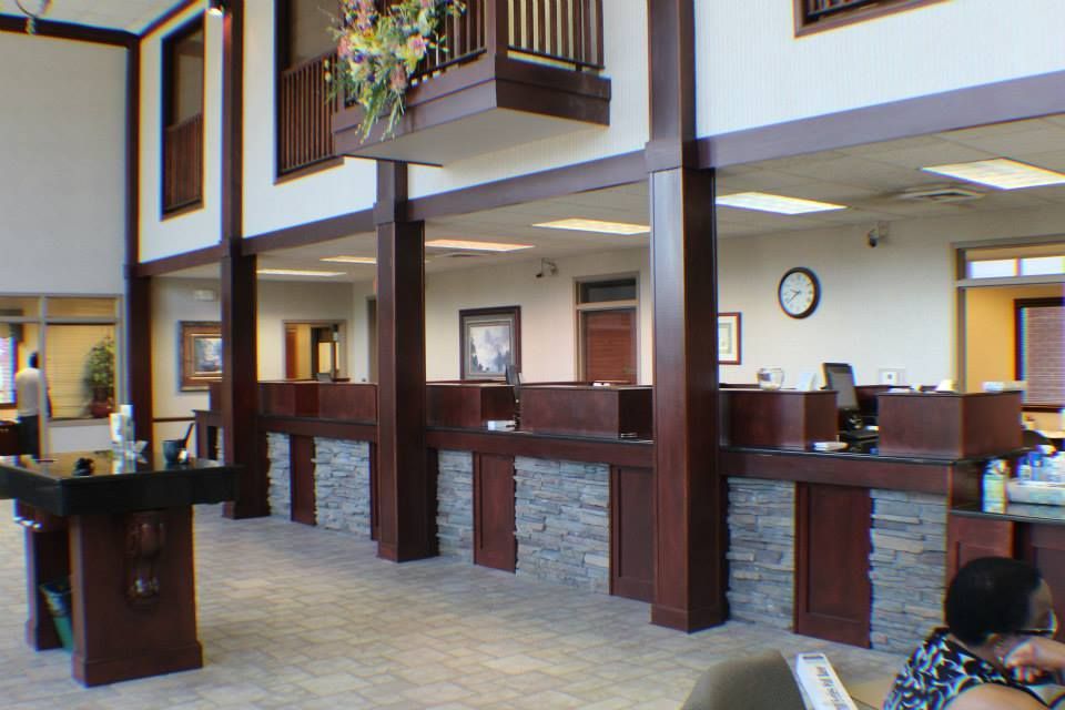 Spacious office lobby with wooden columns, reception counters, and a second-floor balcony.
