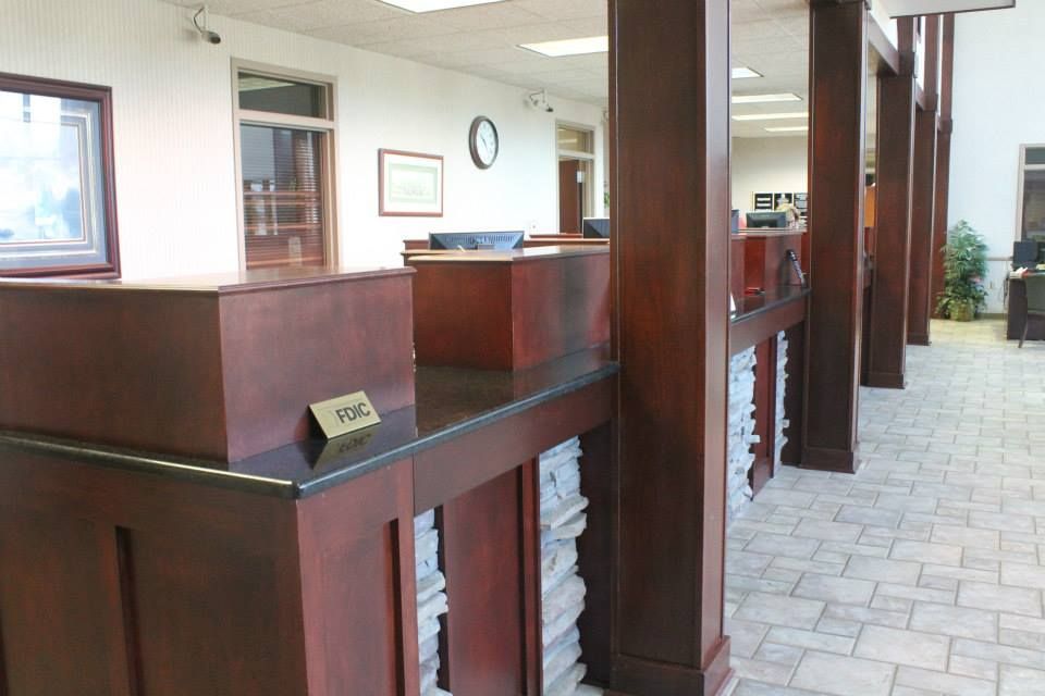 Empty bank lobby with dark wood teller counters and a tiled floor