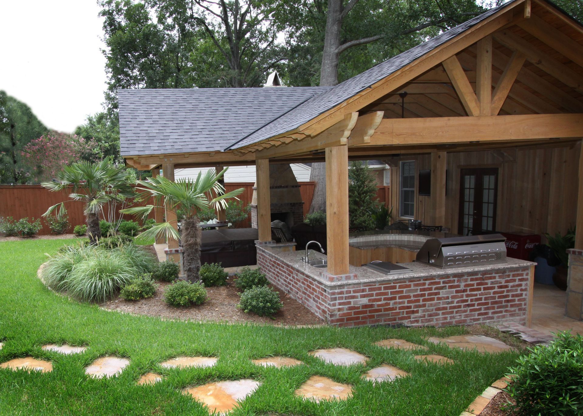 Brick-and-wood house with a covered porch, front yard landscaping, and stepping stones along a green lawn