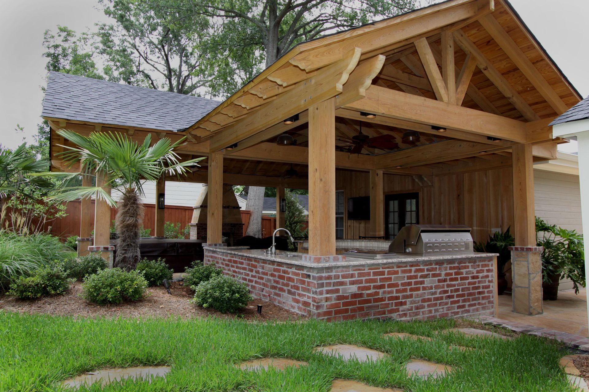 Wooden pavilion with brick base in a green park, surrounded by trees and shrubs.