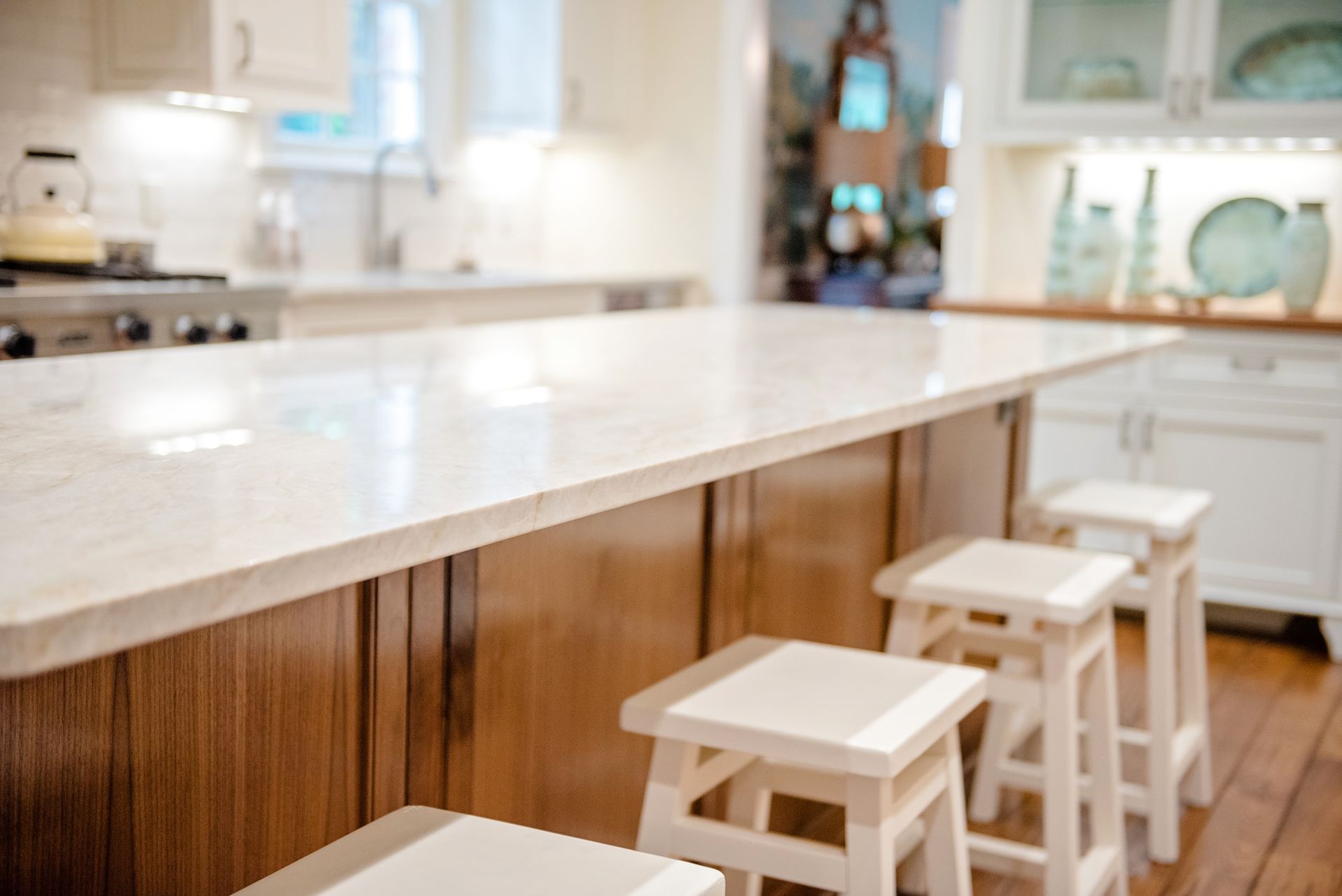 Bright modern kitchen with white marble island and wooden stools