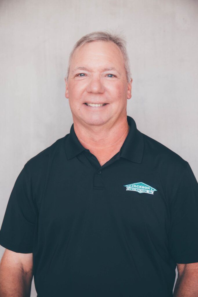 Smiling man in a black polo shirt against a light gray background