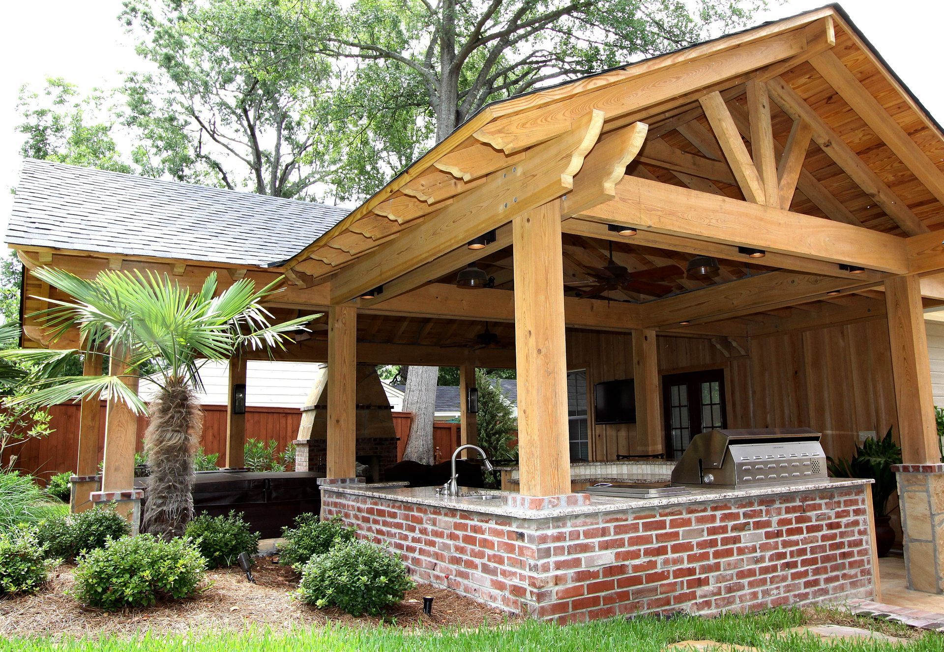Wooden pavilion with brick base and covered roof in a landscaped garden setting