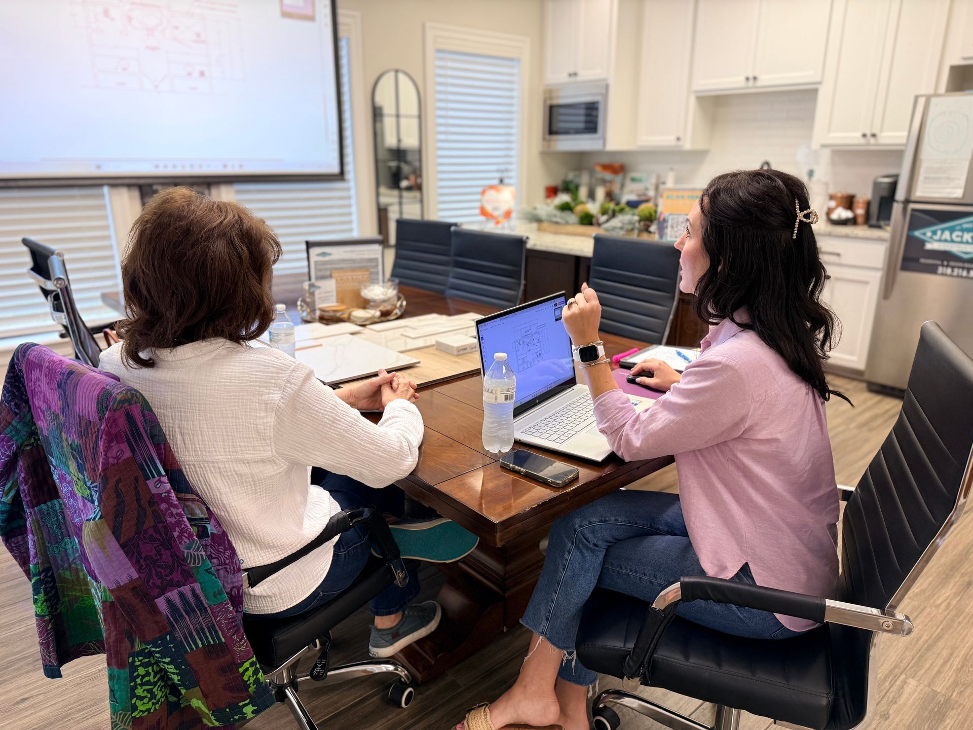 People meeting around a table in a conference room, with laptops and papers spread out.