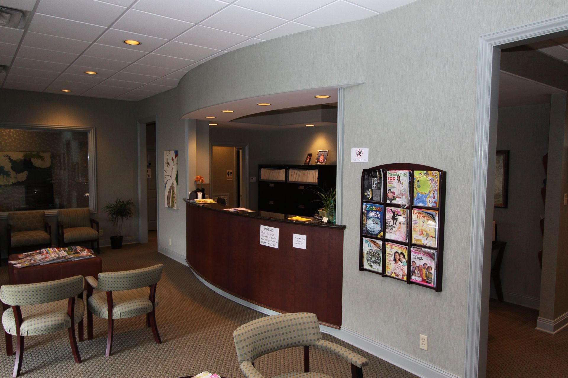 Hotel lobby reception area with curved wood desk, brochure rack, and seating chairs