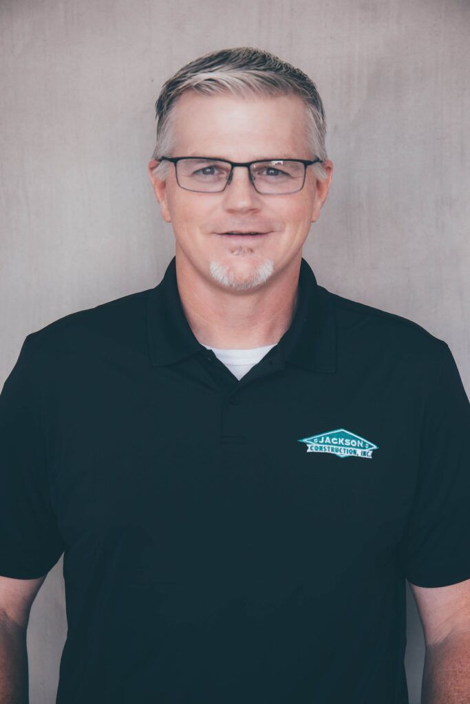 Man in glasses wearing a black polo shirt against a plain gray background