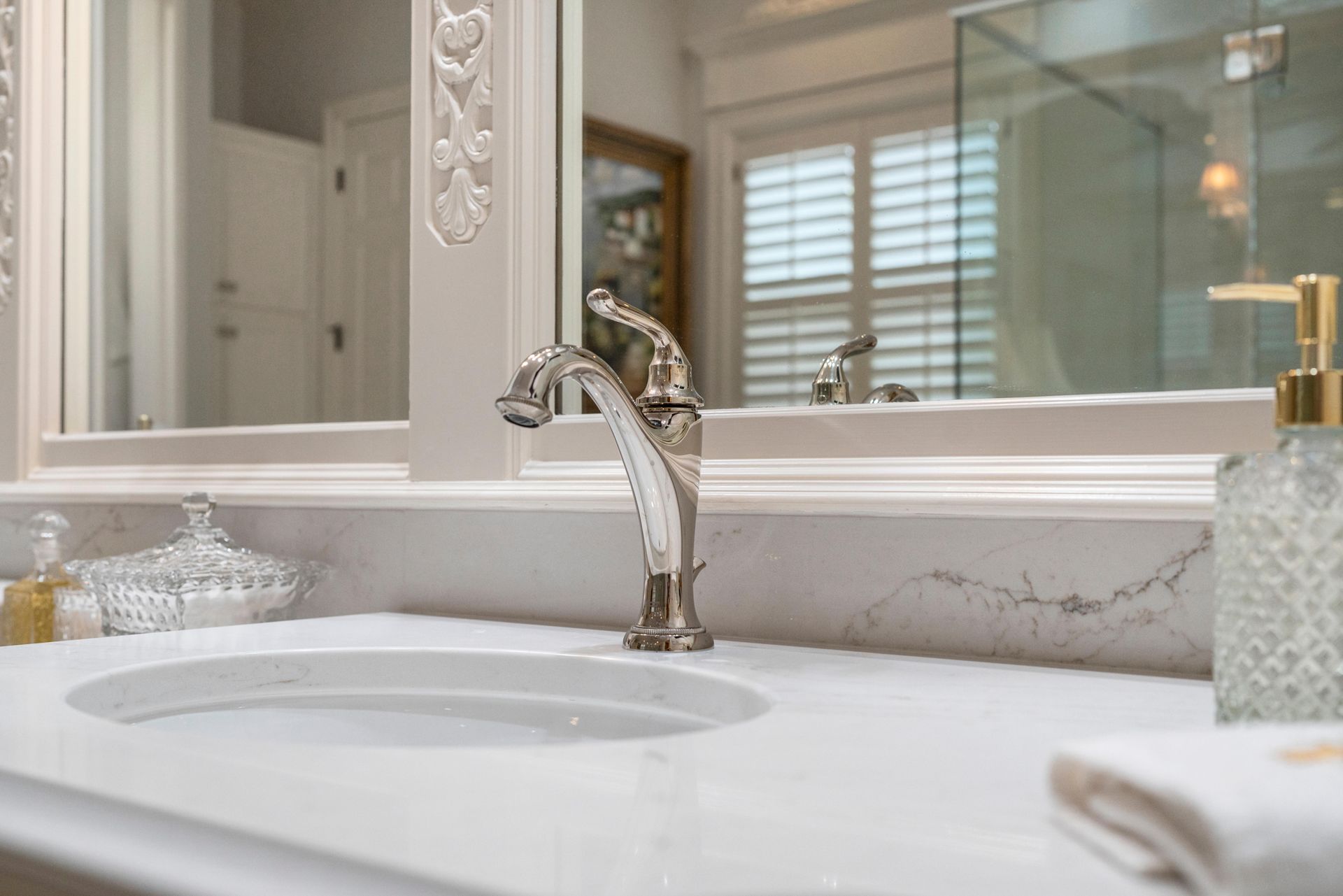 Modern bathroom vanity with white sink, chrome faucet, mirror, and window shutters