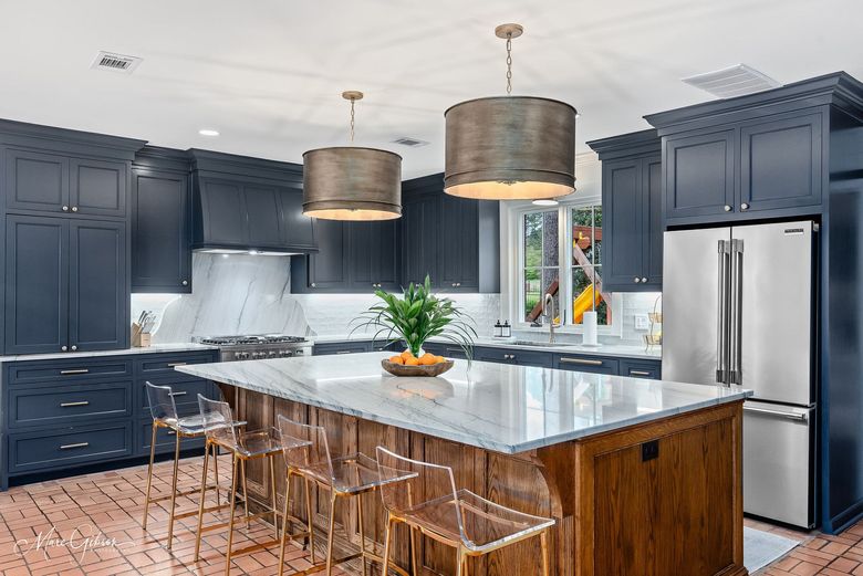 Modern kitchen with dark cabinets, white island, pendant lights, and stainless steel appliances