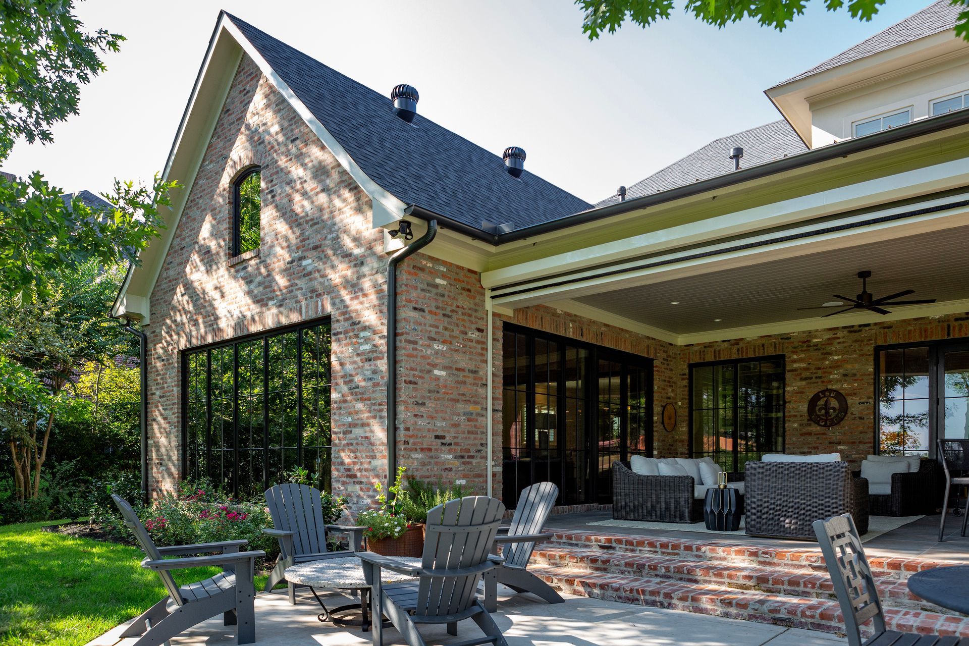 Brick house patio with outdoor seating, covered porch, and open glass doors on a sunny day