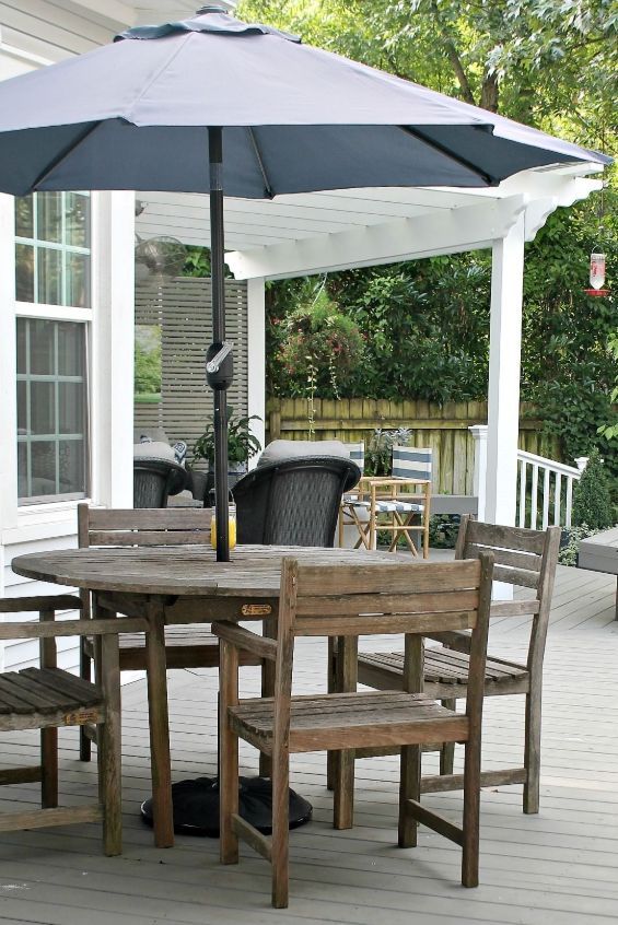 Wooden patio dining set with large black umbrella on a backyard deck