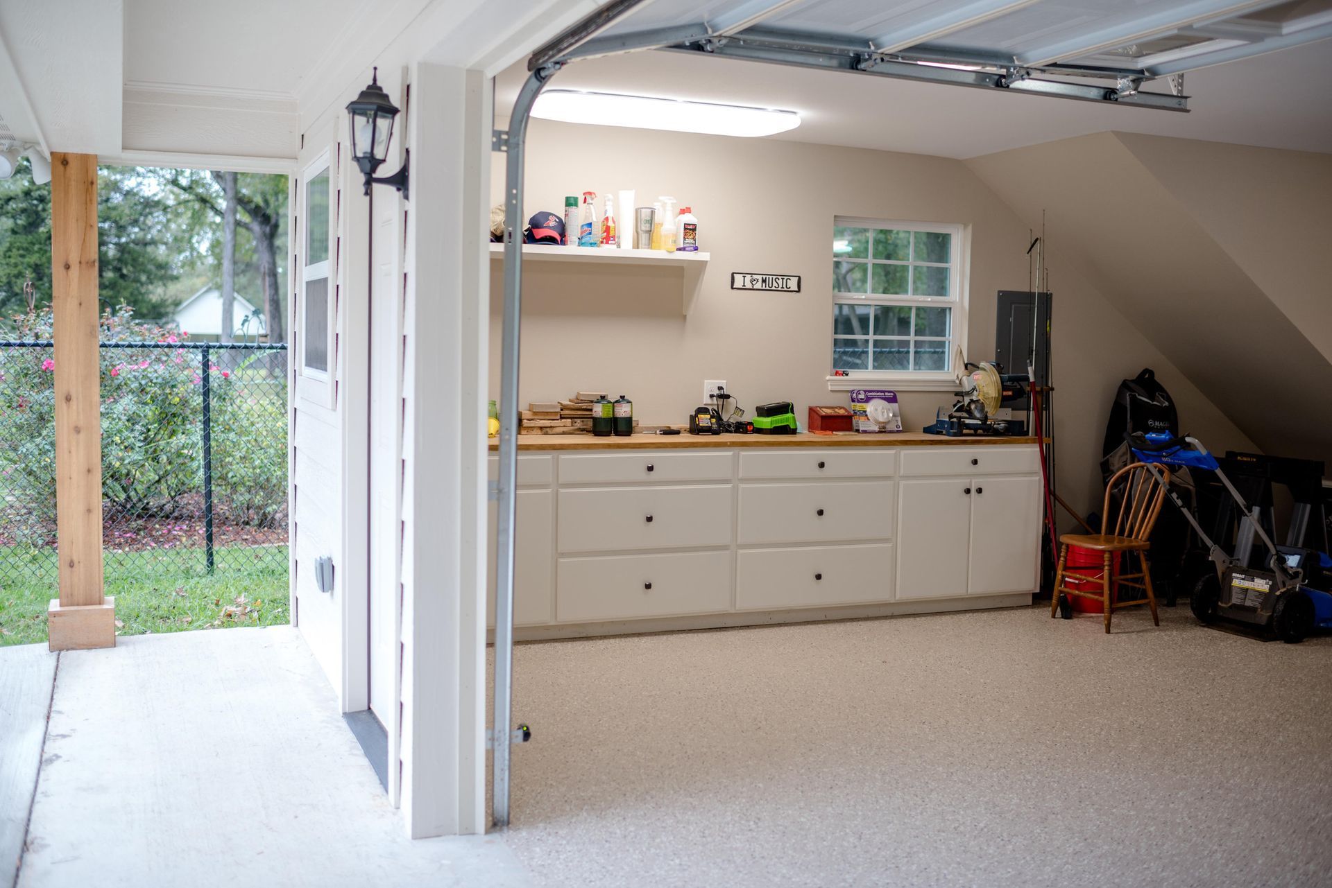 Open garage with workbench, cabinets, and storage shelves in a bright, clean interior.