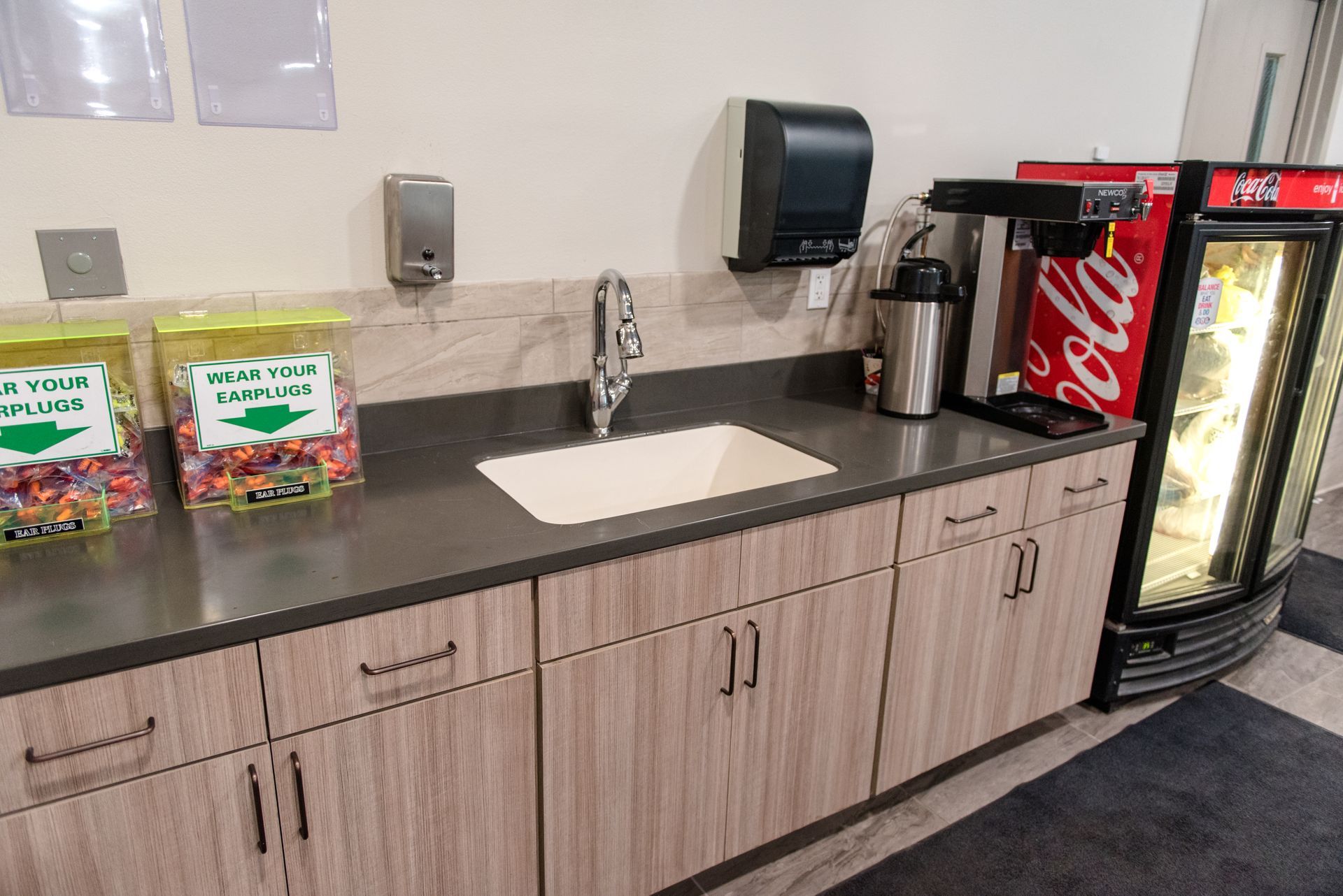 Break room counter with sink, snack jars, paper towel dispenser, and a refrigerated Coke machine