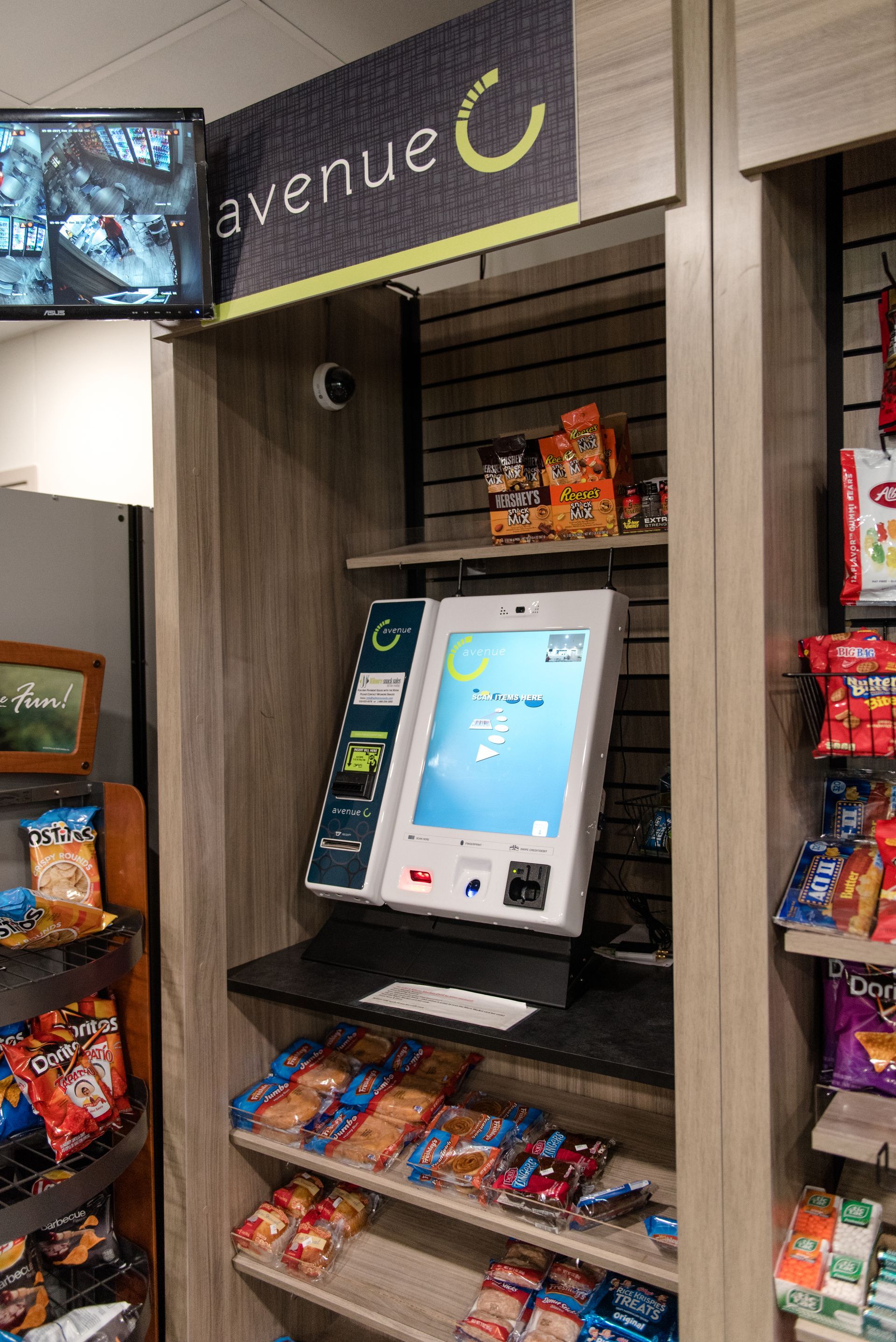 Kiosk screen in a convenience store display with shelves of snacks and drinks around it