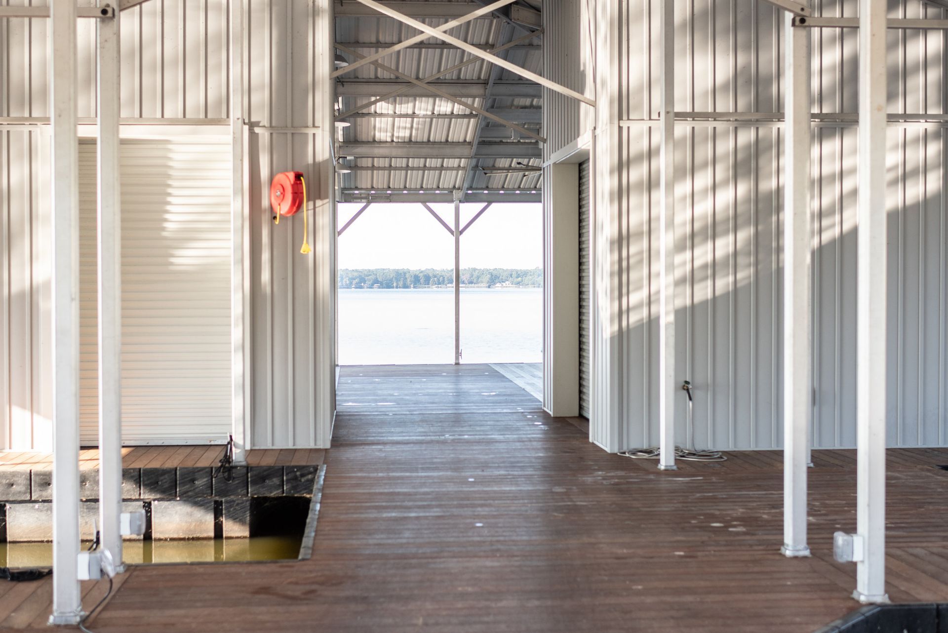 Open-sided wooden walkway with metal posts and bright light at the far end