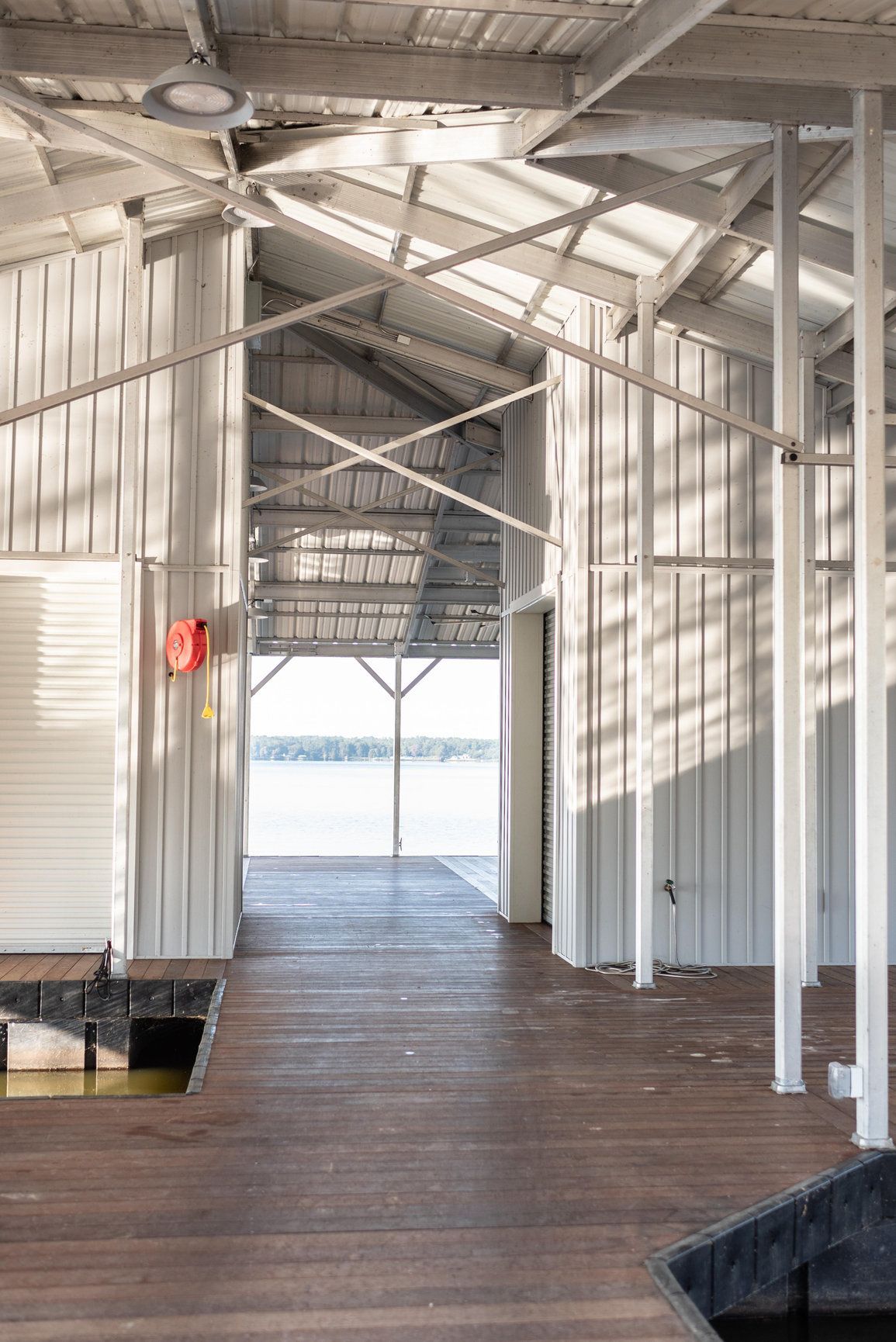 Covered wooden walkway with white metal railings and bright light at the far end