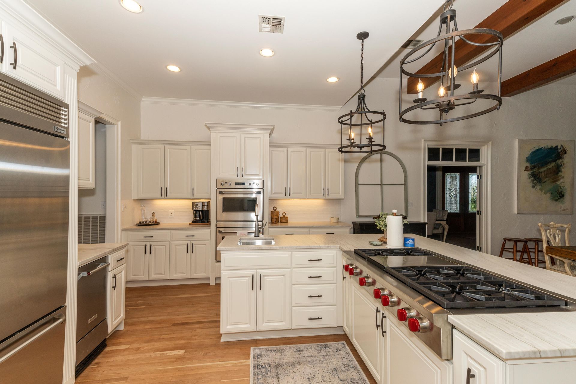 Bright, modern kitchen with white cabinets, stainless appliances, and a large island with a gas cooktop.